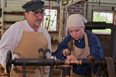 A woman woodturner works as a man instructs her